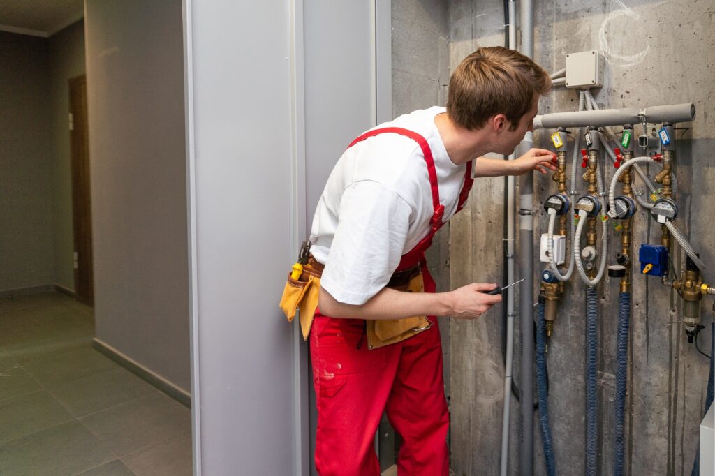 Male plumber fixing water meter with adjustable wrench.